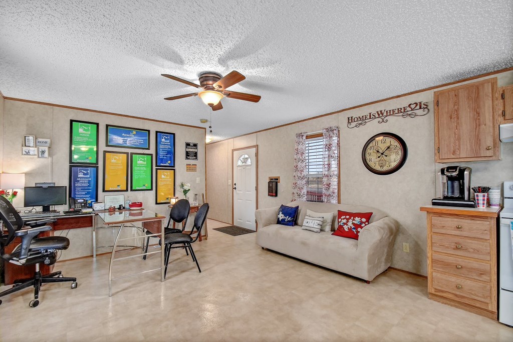 a living room with a ceiling fan and a desk with a computer
