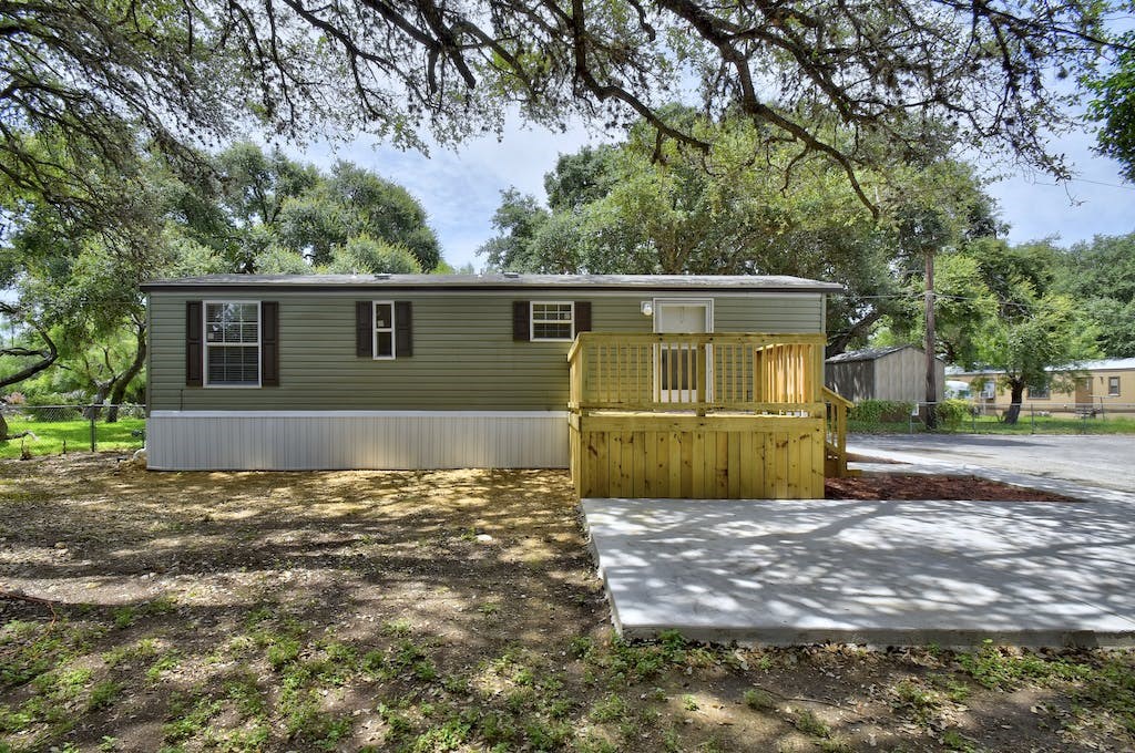 the exterior of a mobile home with a wooden shed and a driveway
