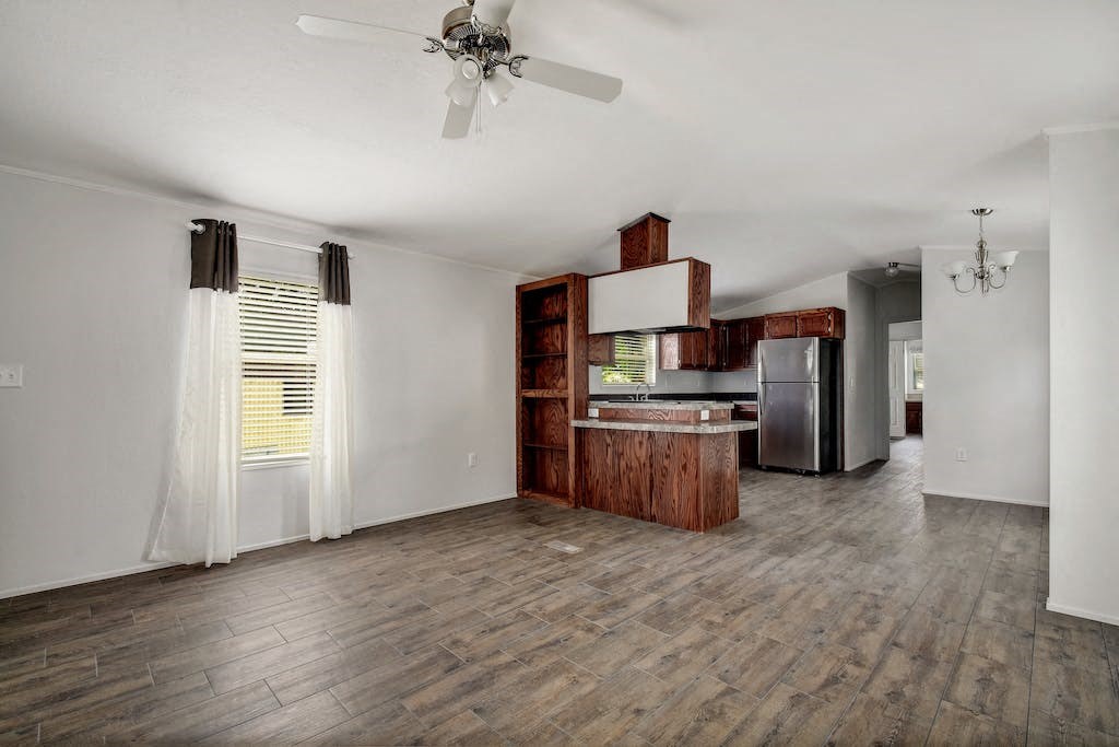 an empty kitchen and living room with a ceiling fan