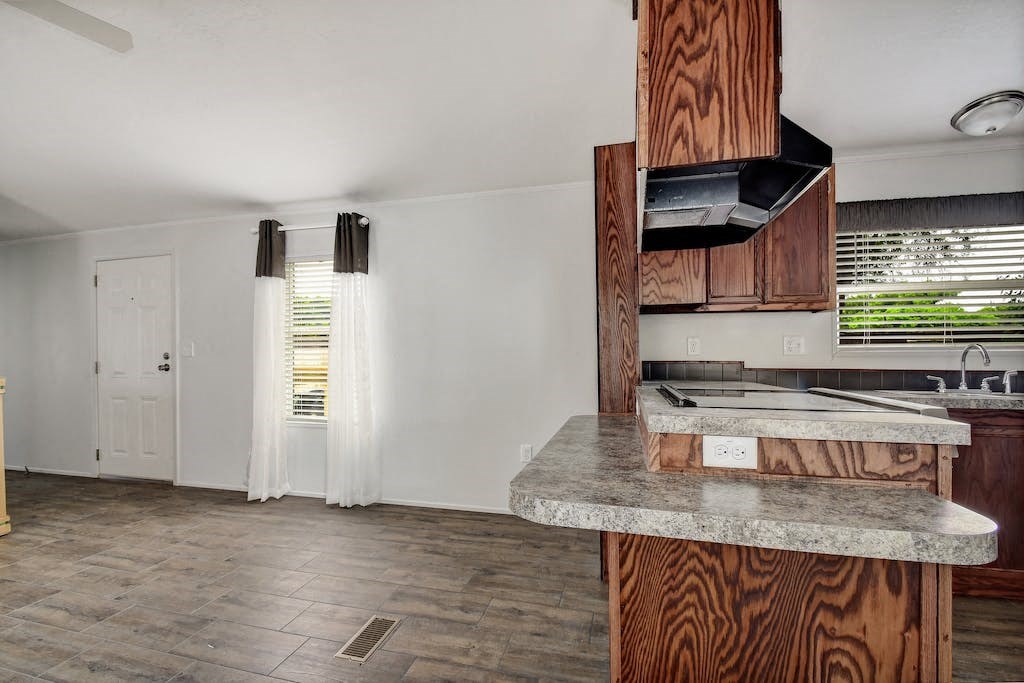 a kitchen and living room with white walls and wood floors