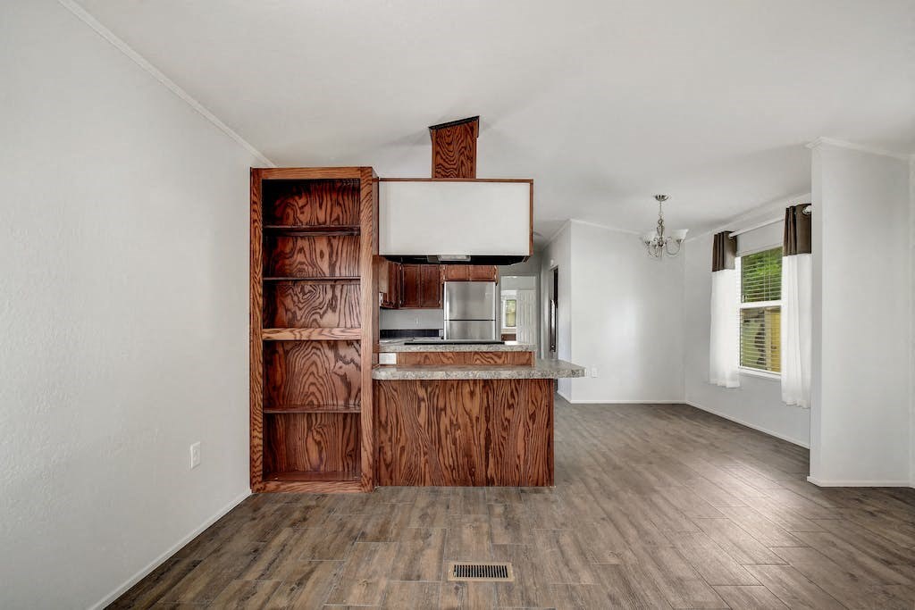 an empty living room with a kitchen with wood cabinets