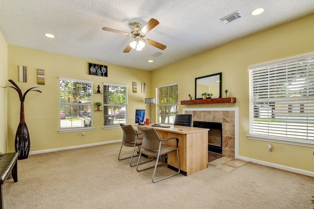 a home office with a fireplace and a ceiling fan