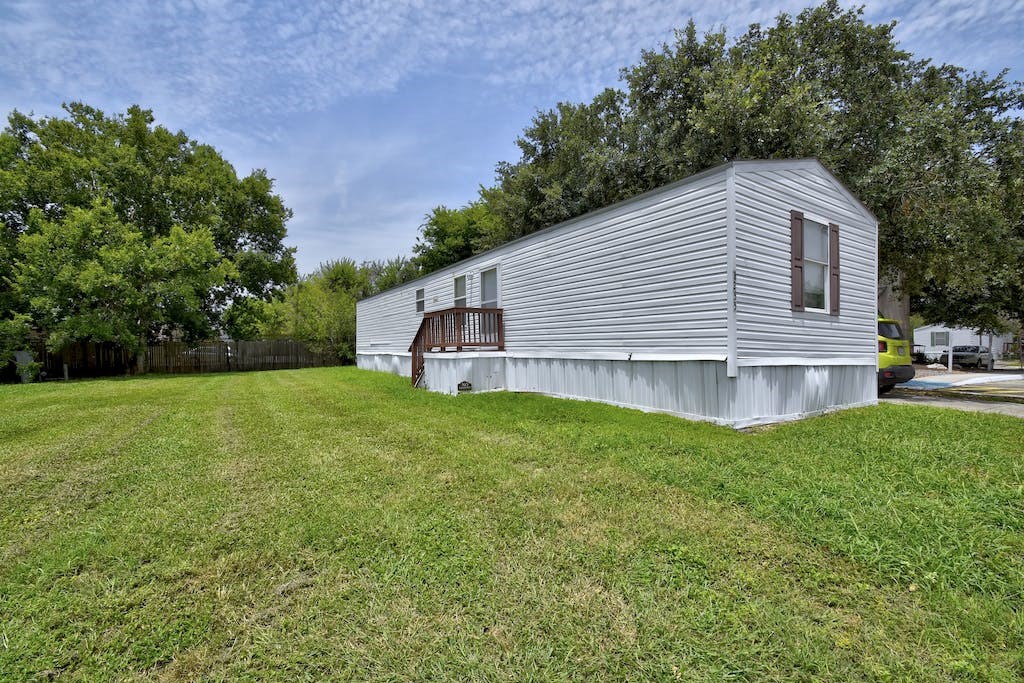 a small white house with a large yard in front of it
