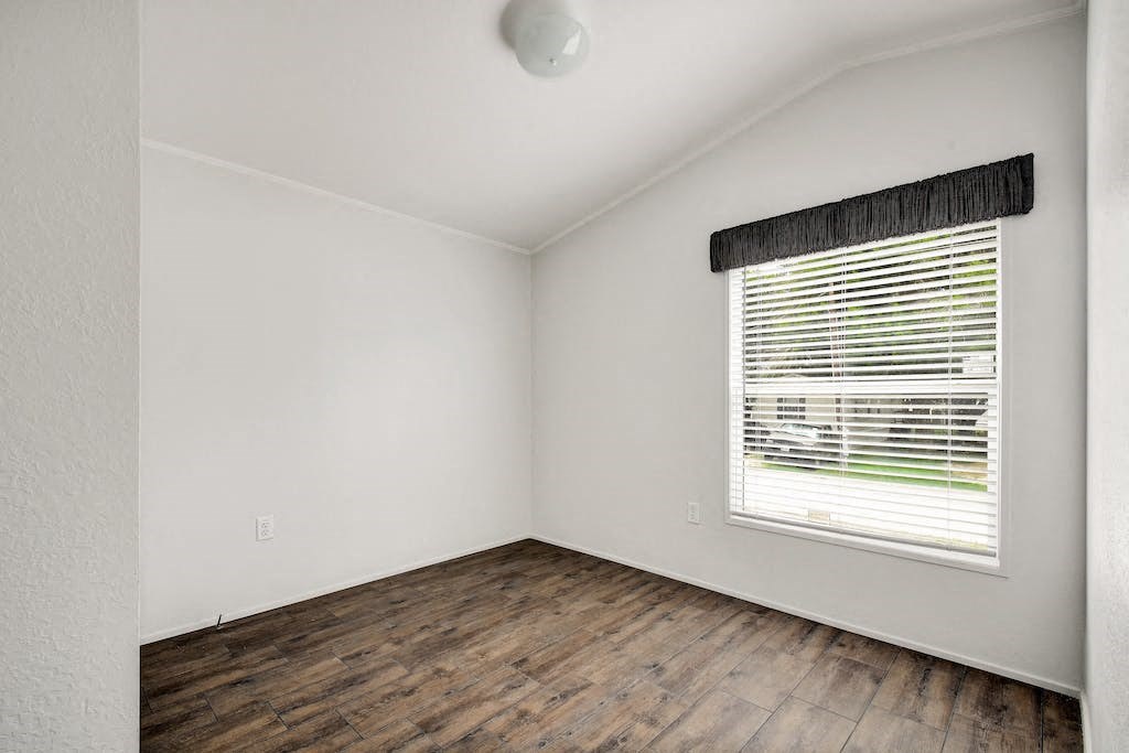 an empty room with a window and wooden floors