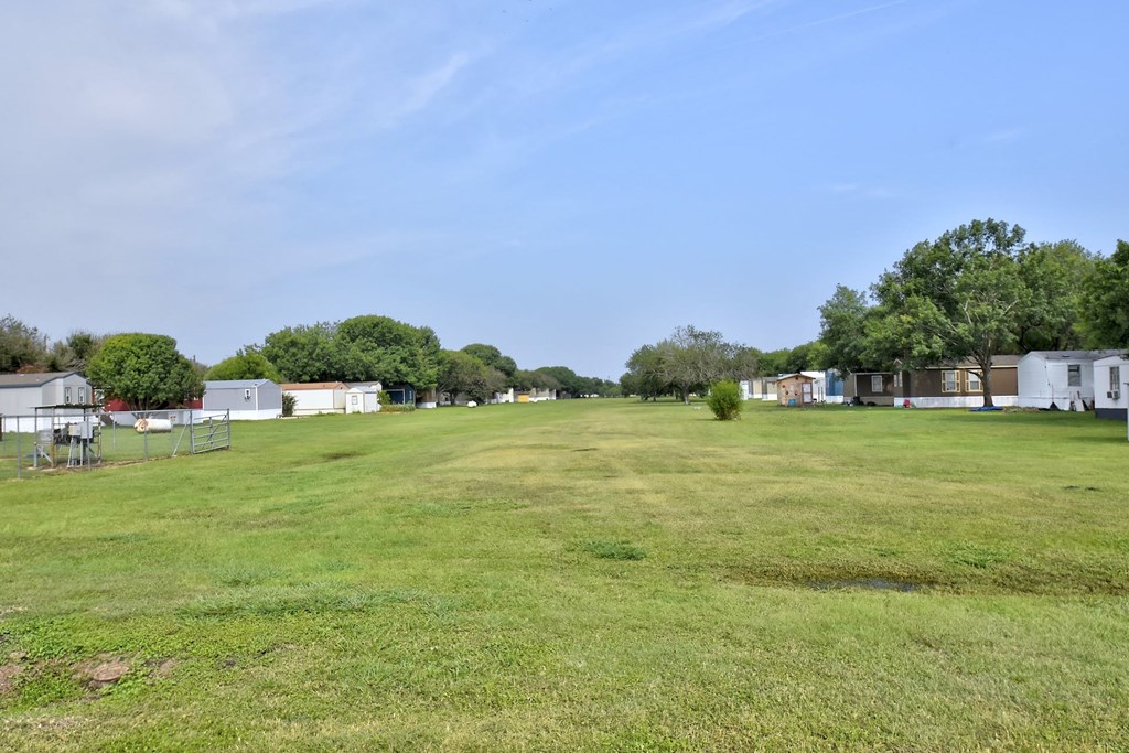 a large grassy field with trailers in the background