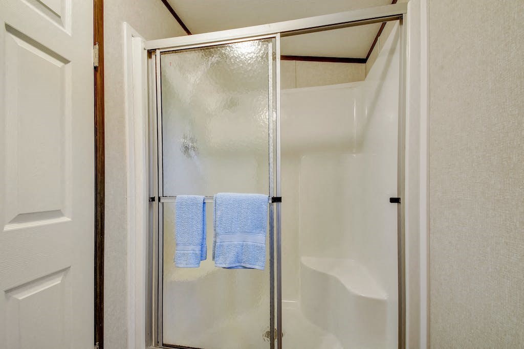 a shower with two blue towels on the door