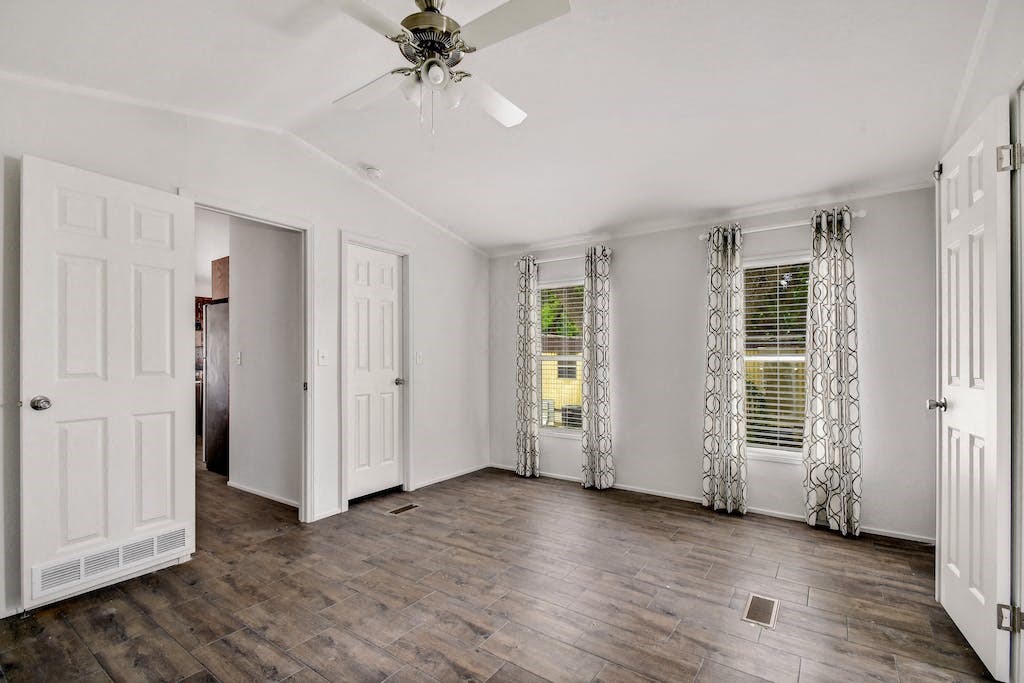 a bedroom with two windows and a ceiling fan