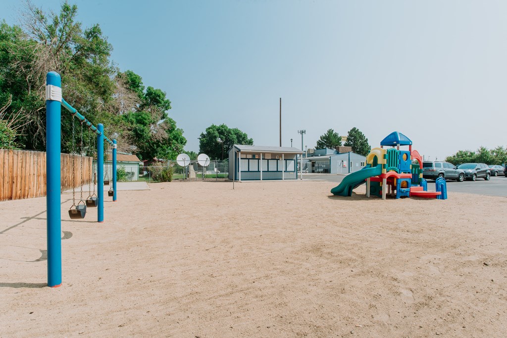 A playground with a blue swing set and a green slide.