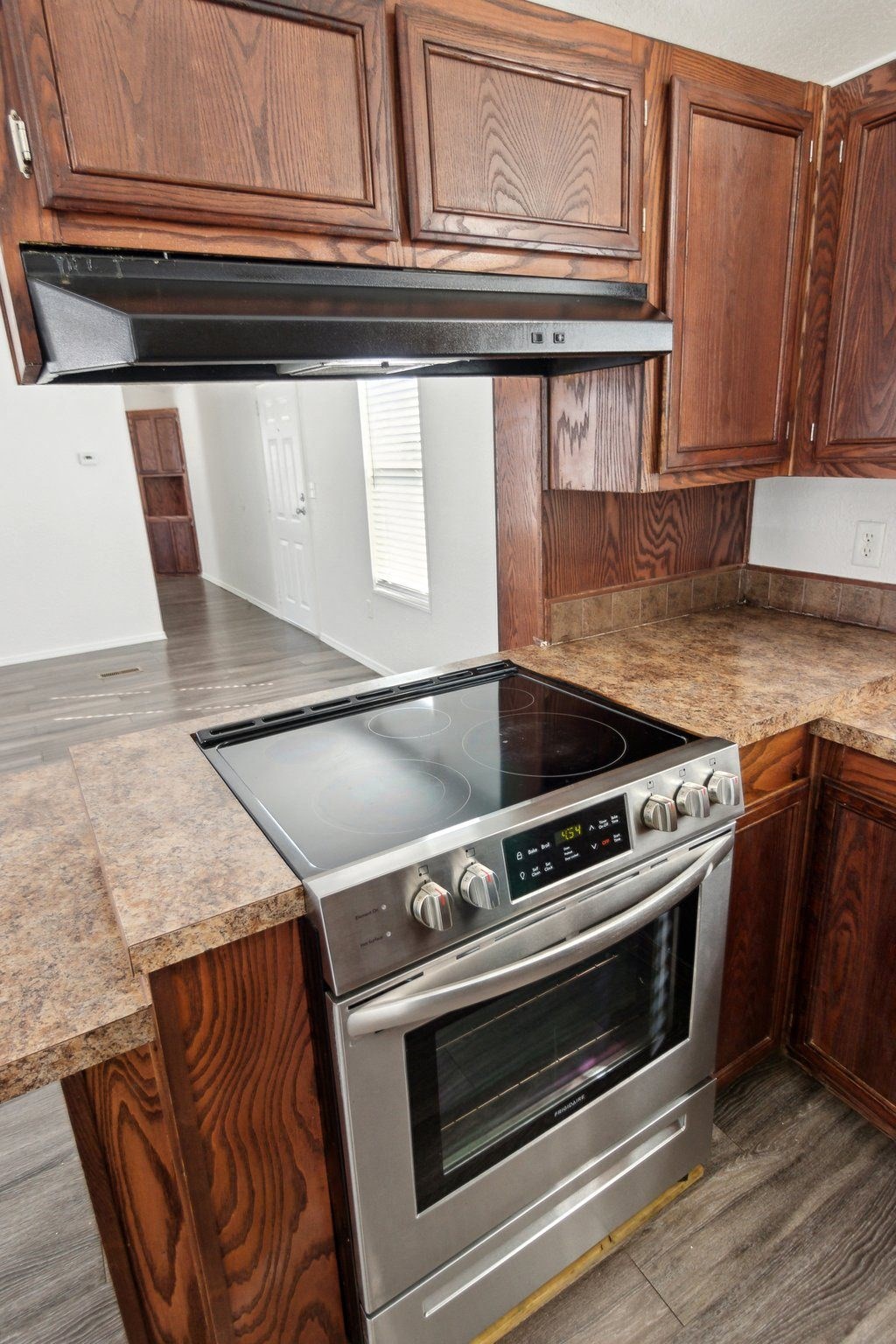 A modern kitchen with a stove top oven and wooden cabinets.