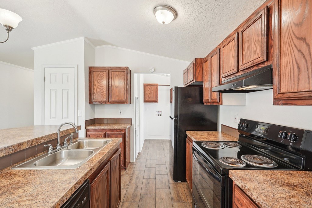 A kitchen with brown cabinets and black appliances.