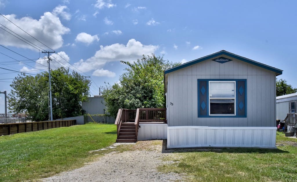 a small white house with a porch and a blue door