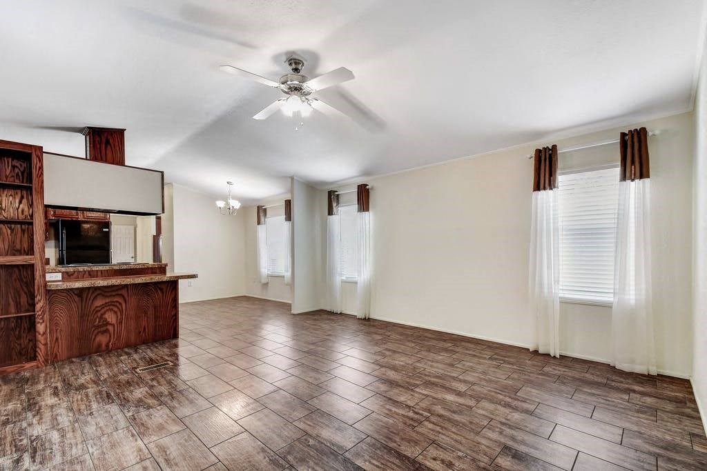 an empty living room with a ceiling fan and a kitchen
