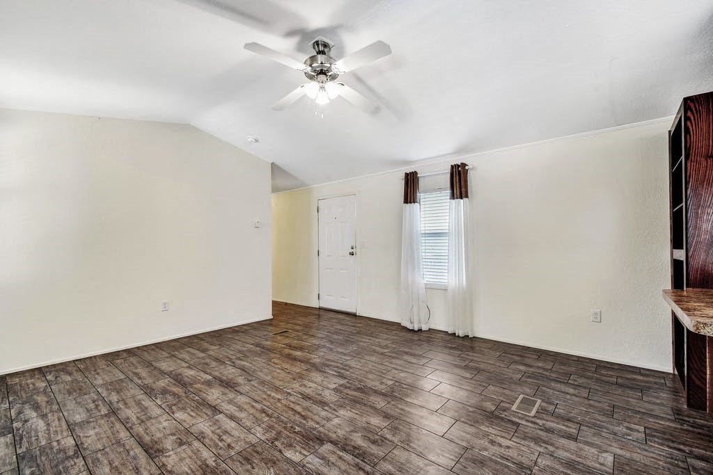 an empty living room with a ceiling fan
