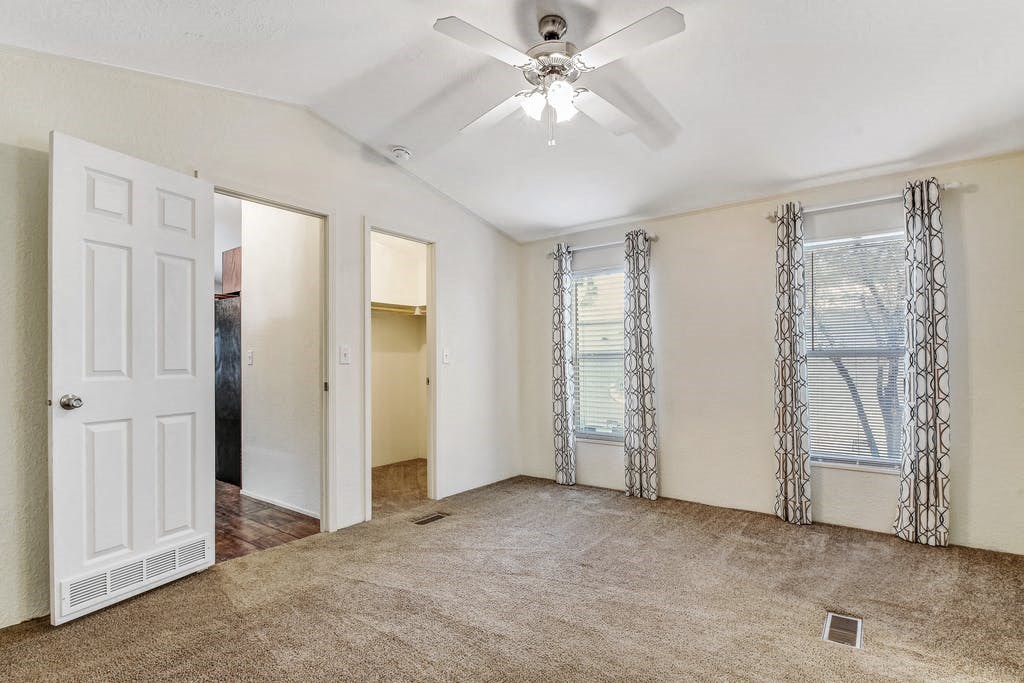 an empty living room with a ceiling fan and a closet