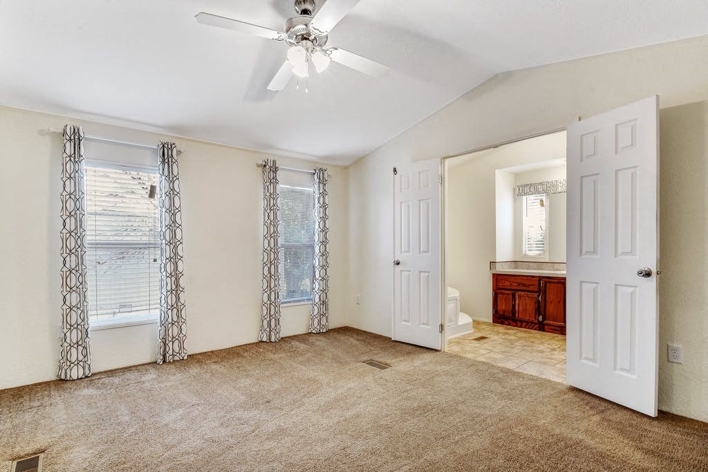 an empty living room with a ceiling fan and a bathroom