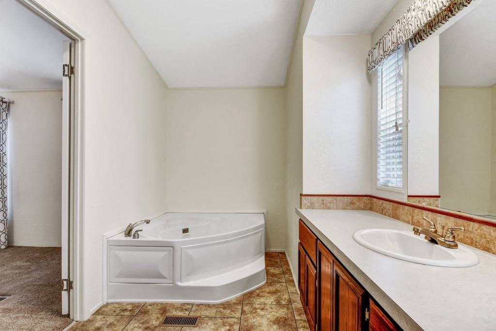 a bathroom with a tub and a sink and a mirror
