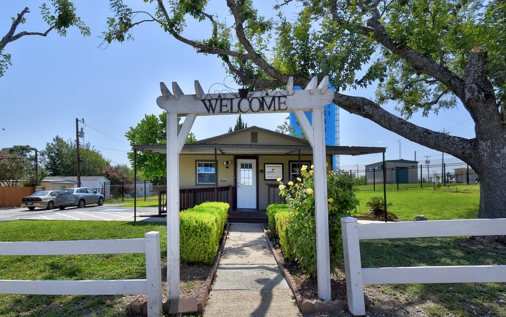 a white gate with the words welcome on it and a white fence in front of it
