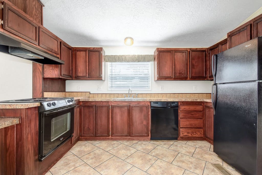 a kitchen with wooden cabinets and a black refrigerator