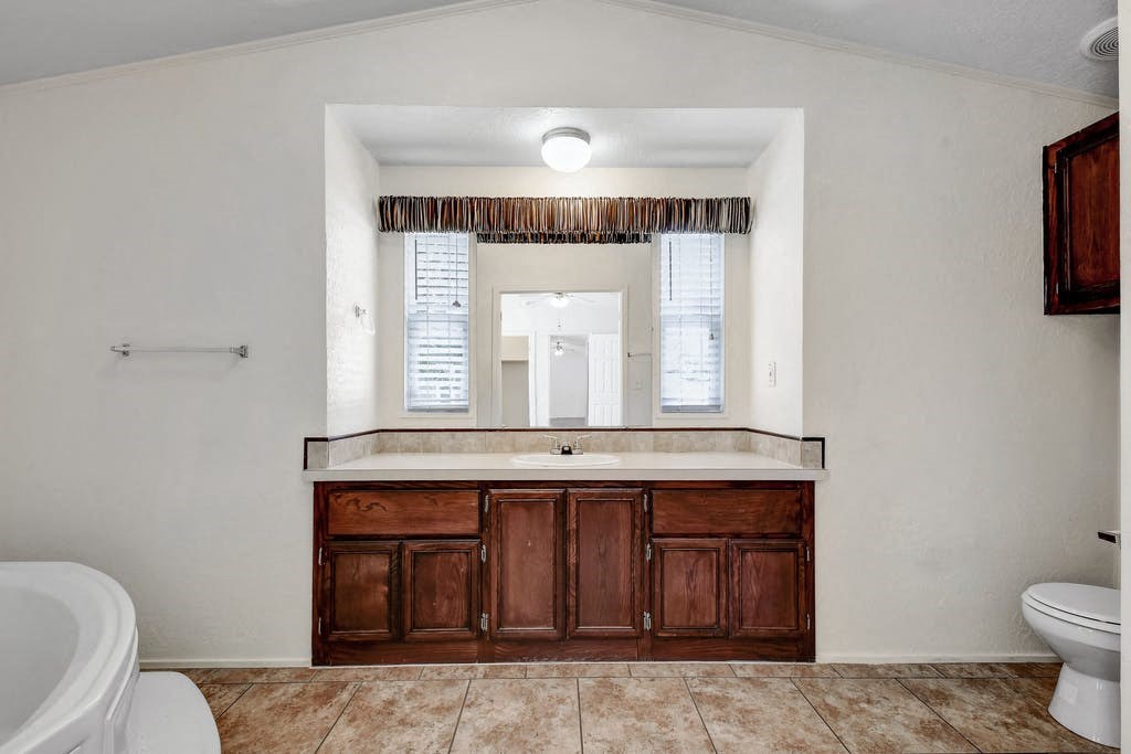 a bathroom with a sink toilet and mirror at Buckingham Village in Universal City, TX