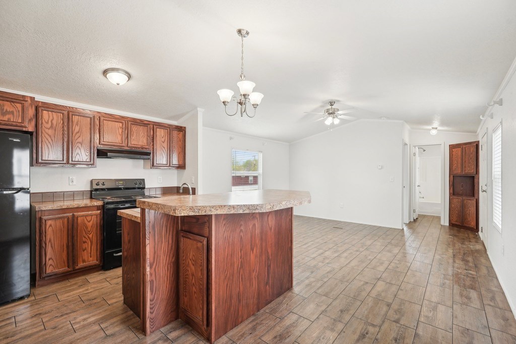 A kitchen with wooden cabinets and a black fridge.
