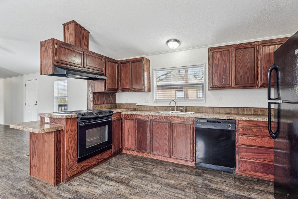 A kitchen with wooden cabinets and black appliances.