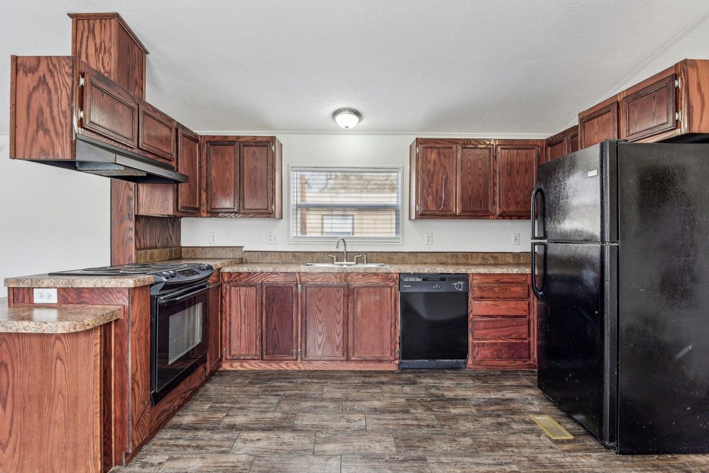 A kitchen with wooden cabinets and black appliances.