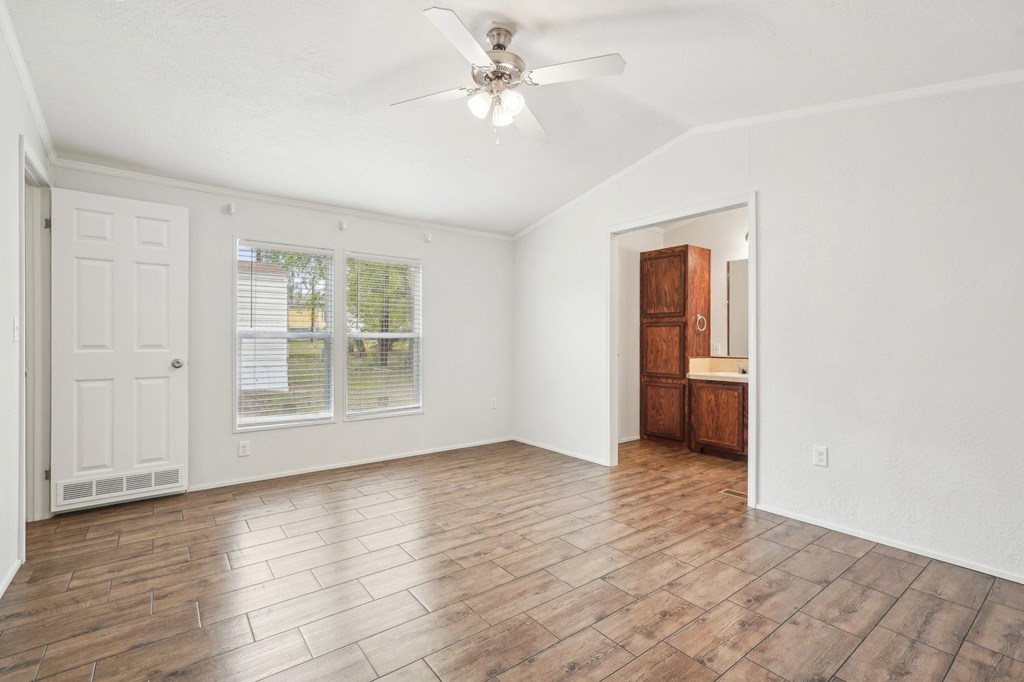 A room with a ceiling fan and wooden flooring.