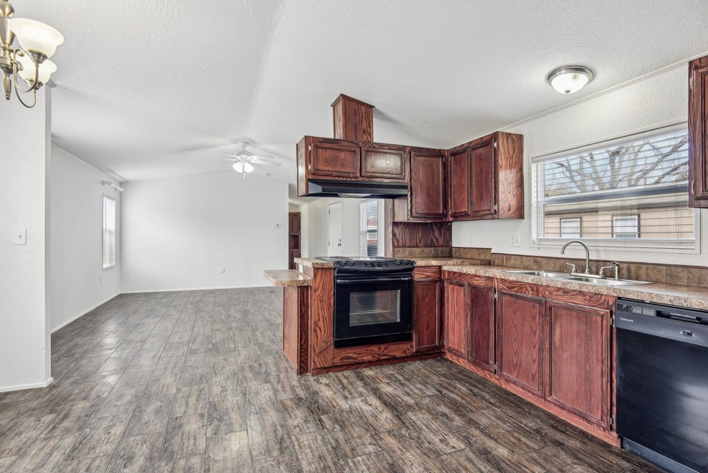 A kitchen with a black oven and wooden cabinets.
