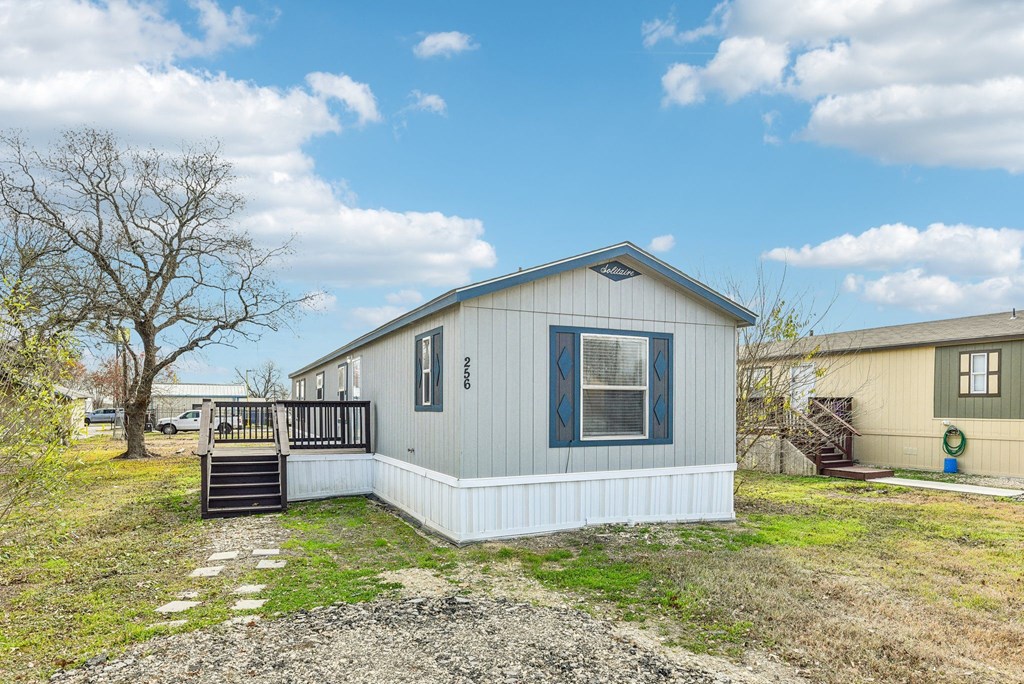 A small house with a porch and a tree in the background.