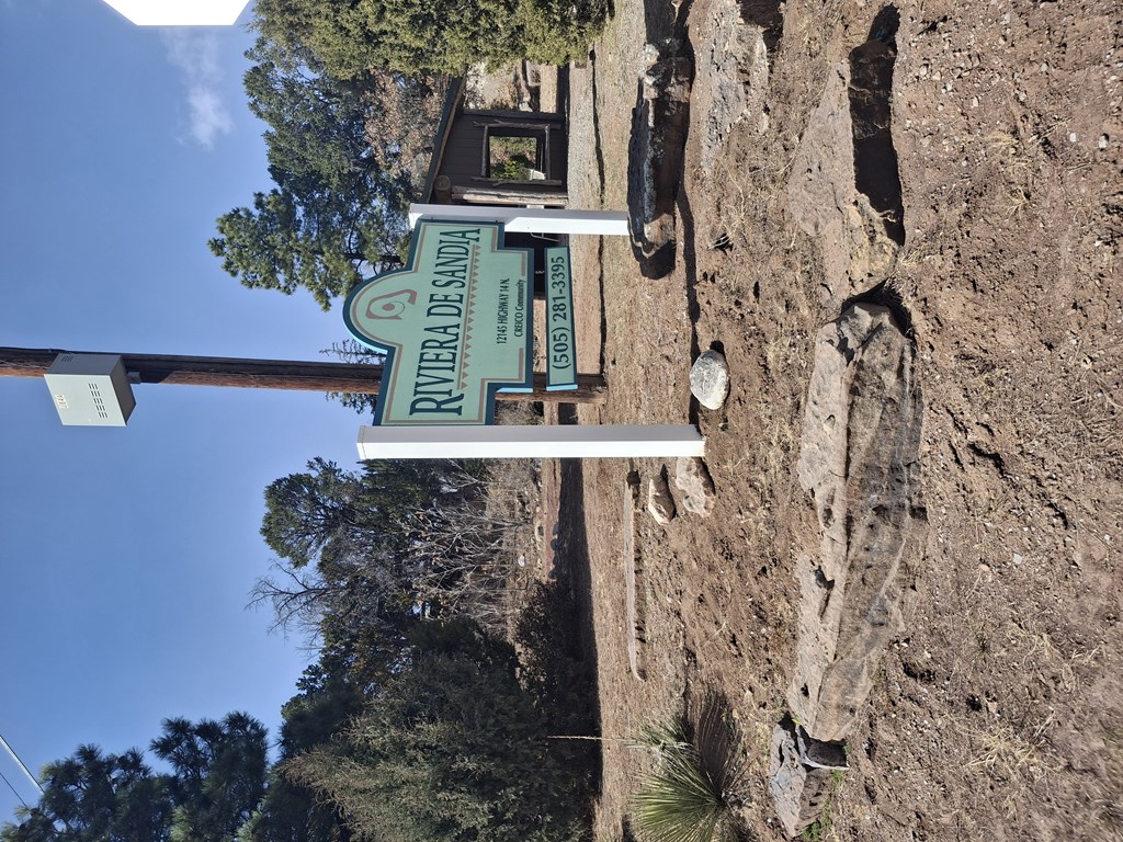 A sign for the Rivera de Arriba is mounted on a rocky wall.