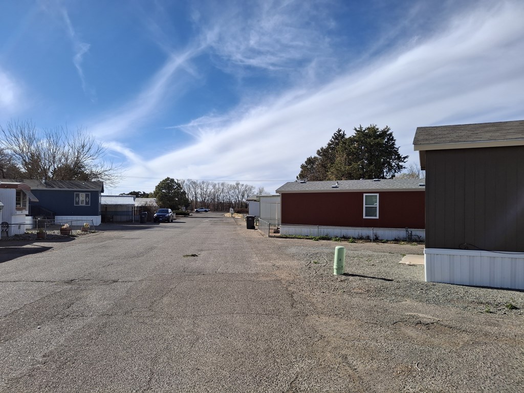 A gravel lot with a blue house and a red building.