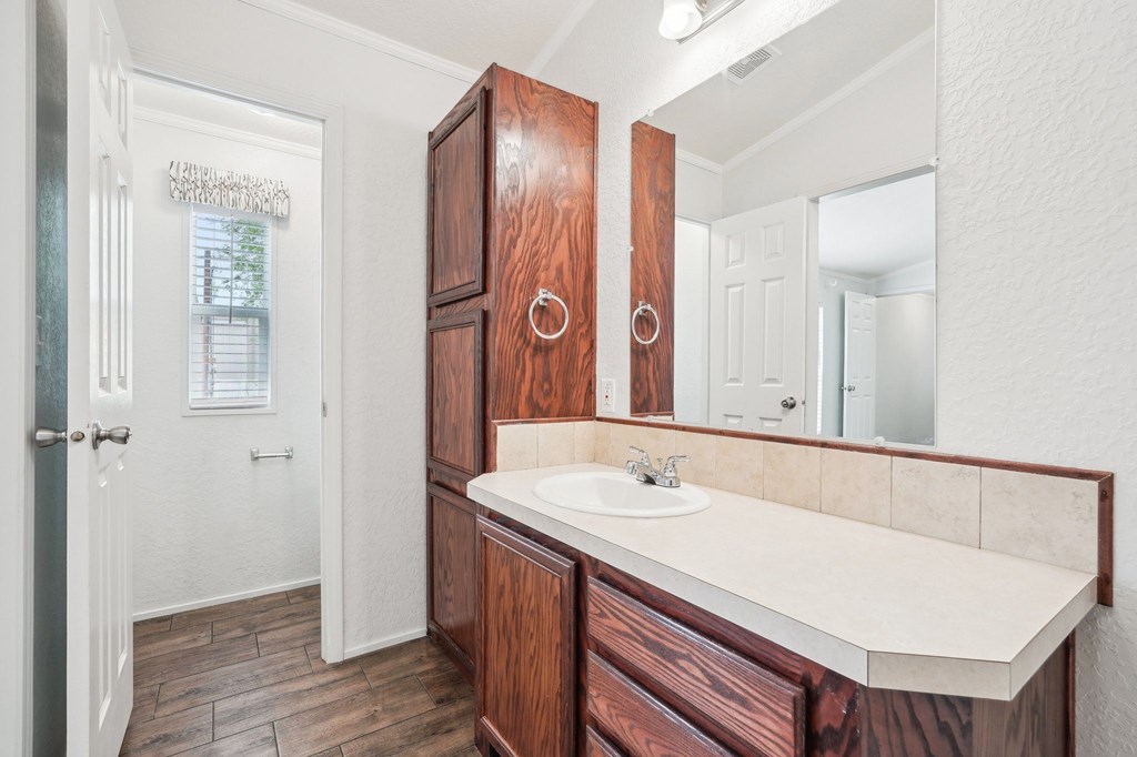 A bathroom with a sink, mirror, and wooden cabinets.