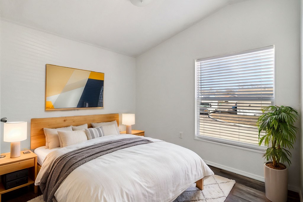 A bedroom with a large bed and a painting on the wall.