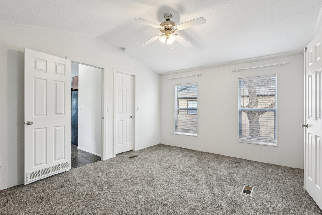 A room with a ceiling fan and a window with blinds.