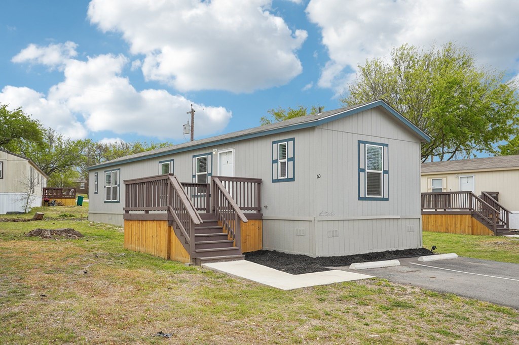 A small house with a wooden deck and stairs leading to the front door.