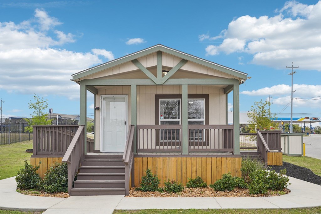 A small house with a porch and a white door.