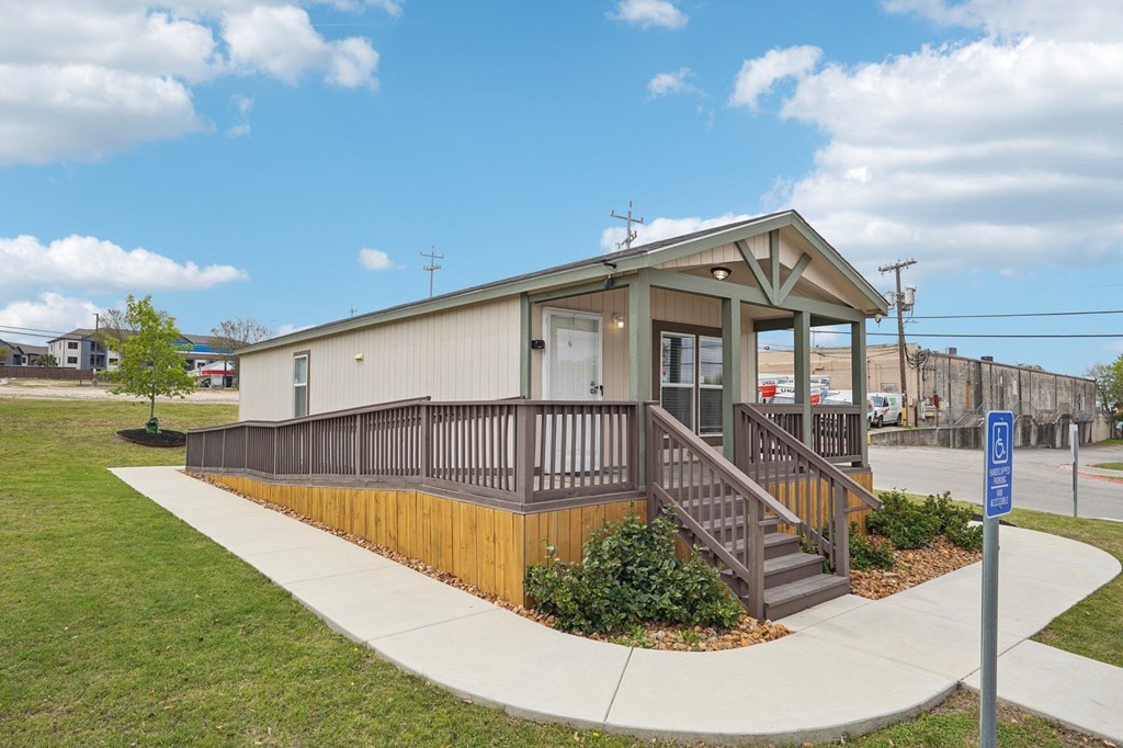 A small building with a brown and white exterior and a wooden deck.