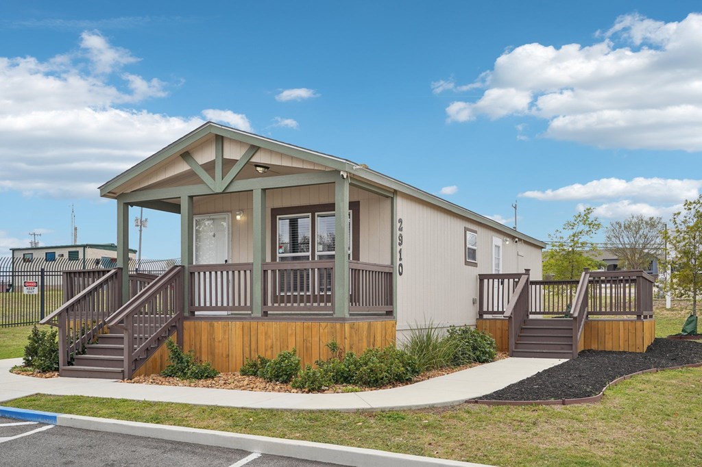 A small house with a porch and a brown staircase.
