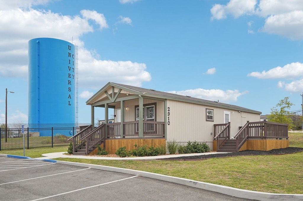 A small building with a porch and a blue water tower in the background.