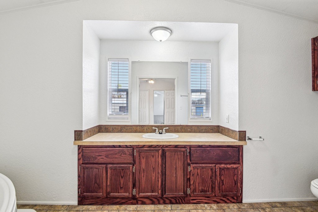 A bathroom with a wooden vanity and a large mirror.