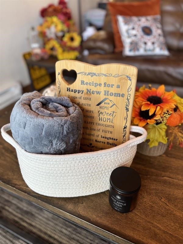 A bowl with a rolled-up grey towel, a recipe book, and a small jar on a wooden surface.