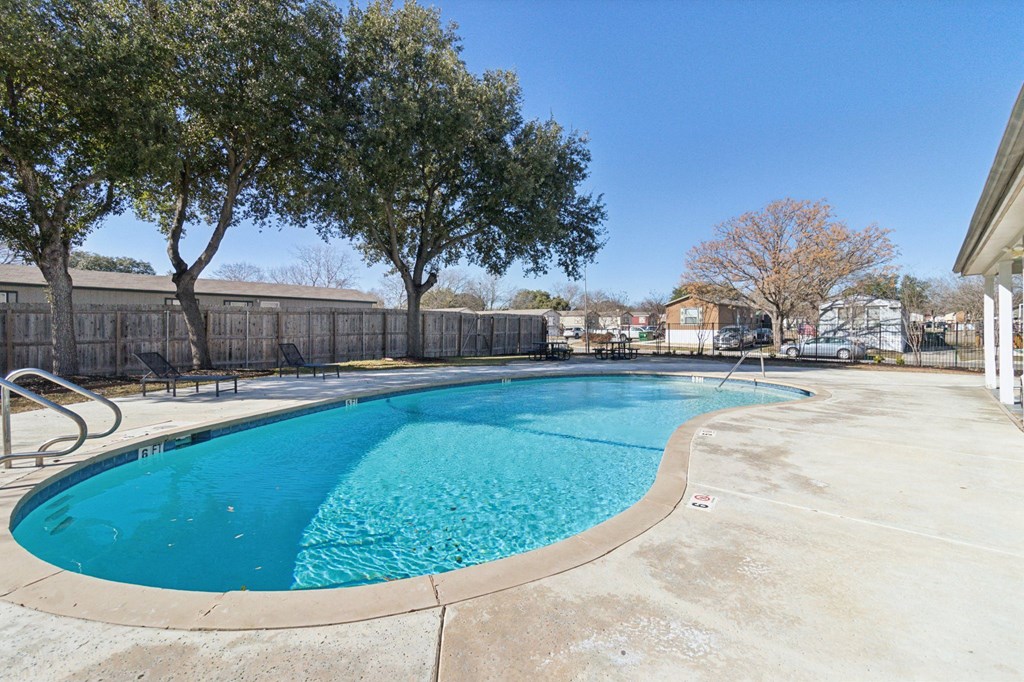 A large outdoor swimming pool surrounded by trees.