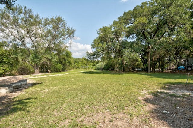 a large grassy field with trees and a campsite