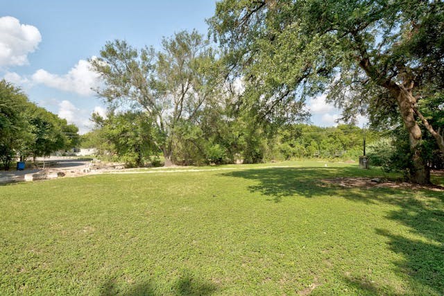 a field of grass with trees and a river