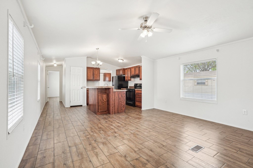 A spacious kitchen with wooden floors and white walls.