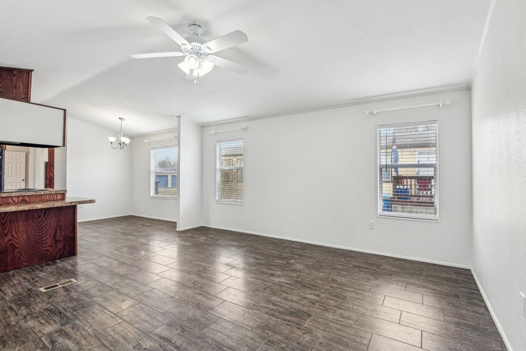 A room with a ceiling fan and a wall with pictures on it.