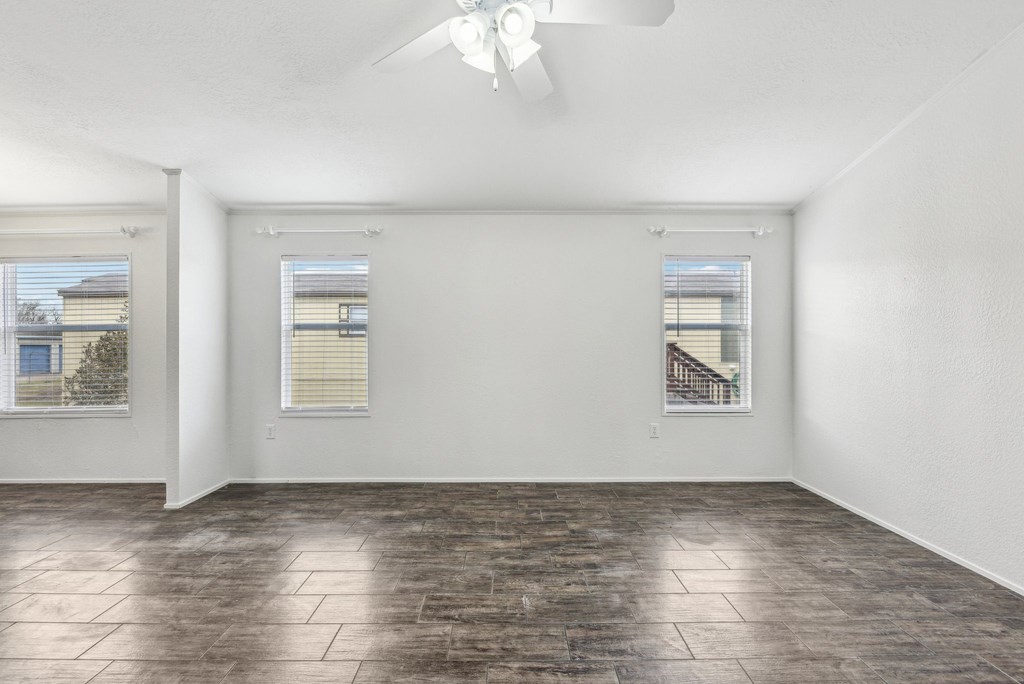 A room with a ceiling fan and two windows.