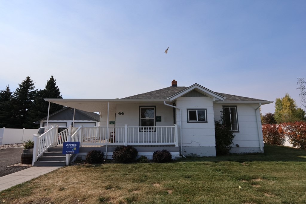 a white house with a porch and a bird flying over it at Country Lane, Cheyenne