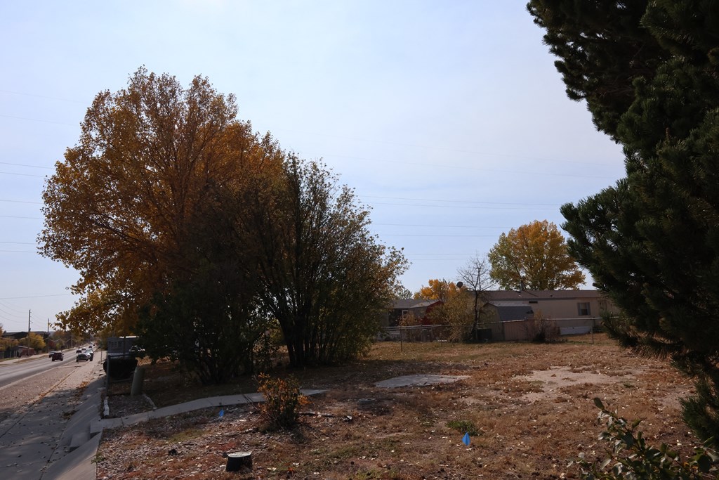 an empty lot next to a road with trees and a house at Country Lane, Wyoming, 82007