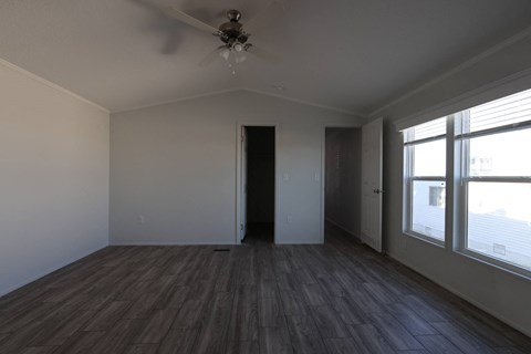an empty living room with wood floors and a ceiling fan